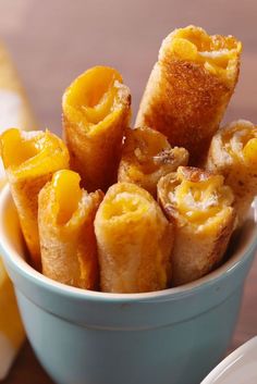 a blue bowl filled with fried food on top of a wooden table next to plates