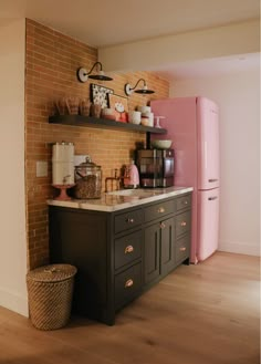 a kitchen with brick wall and pink refrigerator