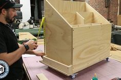 a man standing next to a large wooden box on top of a workbench