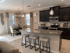 a kitchen with an island and bar stools next to the counter top in front of it