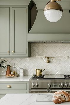 a kitchen with green cabinets and white counter tops, gold accents on the oven hood