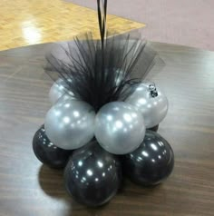 some black and white balloons are on a wooden table with a flower in the middle