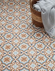 a basket sitting on top of a floor next to a blue and brown tile pattern