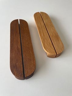 two pieces of wood sitting next to each other on a white surface with one wooden object in the foreground