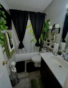 a bathroom with black and green decor in the shower curtain, toilet, sink and mirror