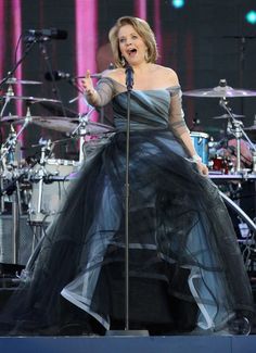 a woman in a black dress singing on stage