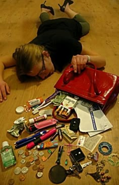 a woman laying on the floor with her purse full of money and other items scattered around