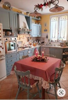 a kitchen with blue cabinets and a table covered in a red checkered tablecloth