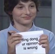 a woman holding up a piece of paper that says ding dong ur opinion is wrong