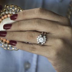 a woman's hand holding a ring with pearls on it and a diamond in the middle