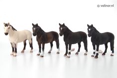 five toy horses lined up in a row on a white surface with one horse facing the camera