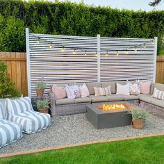 a fire pit in the middle of a backyard with striped cushions and pillows on it