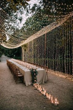 a long table set up with candles and greenery for an outdoor wedding reception in the woods