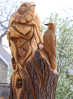 a carved wooden bird sitting on top of a tree