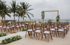 an outdoor ceremony set up with chairs and flowers on the floor next to palm trees