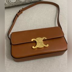 Celine Triomphe Tan Brown Natural Calfskin Shoulder Bag 8 X 5 X 2 In (20.5 X 11.5 X 4 Cm) Natural Calfskin Lambskin Lining Gold Finishing Triomphe Metallic Closure One Main Compartment One Inner Flat Pocket Adjustable Strap With A Minimum Drop 8 In (21 Cm) And Maximum Drop 10 In (25 Cm) Pre Owned In Excellent Condition. There Are Some Minor Scratches As Shown. There Is One Minor Discoloration Inside The Pocket As Shown In Picture Number 16 There Is No Dust Bag. Celine Brown Bag, Luxury Tan Rectangular Shoulder Bag, Luxury Tan Bucket Shoulder Bag, Tan Calf Leather Shoulder Bag With Branded Hardware, Luxury Tan Bag With Leather Lining, Elegant Tan Shoulder Bag With Dust Bag, Luxury Gold Shoulder Bag With Leather Lining, Luxury Tan Leather Shoulder Bag, Timeless Gold Shoulder Bag With Leather Lining