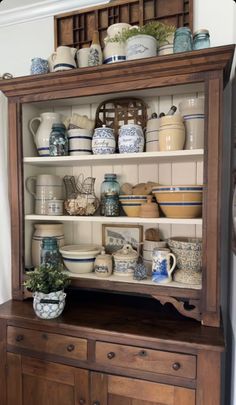 an old china cabinet is filled with dishes and vases on it's shelves