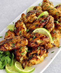 chicken wings with limes and cilantro on a white plate