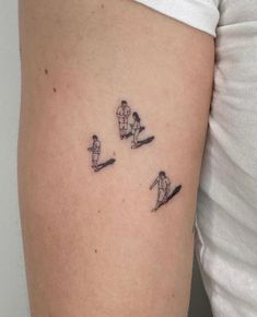 a woman's arm with three small tattoos on the side of her body, depicting two skiers skiing