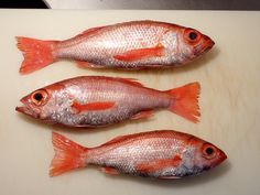 three fish sitting on top of a cutting board