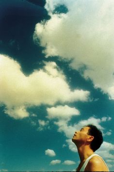 a man looking up into the sky with clouds in the background