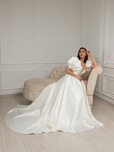 a woman in a white wedding dress sitting on a couch with her hands behind her head