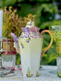 a table topped with vases filled with flowers next to candles and other items on top of a table