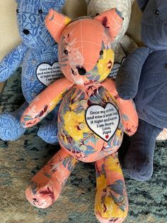 three stuffed animals sitting next to each other on a carpeted area with blue and white walls