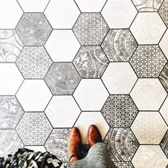 someone is standing in front of a wall with hexagonal tiles on the floor