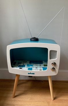 an old fashioned television set sitting on top of a wooden floor next to a wall