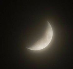 the moon is seen in the dark sky during a partial solar eclipse on jan 25, 2013