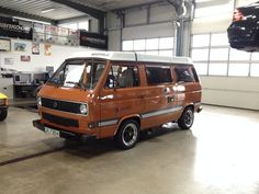 an orange van parked in a garage next to a yellow car and another vehicle behind it