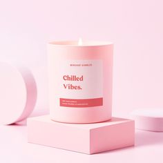 a pink candle sitting on top of a box next to a white container with the words chilled vibes written on it