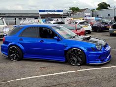 a blue car parked in a parking lot next to other cars