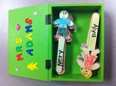 two wooden toy figures in a green box with writing on the front and back sides