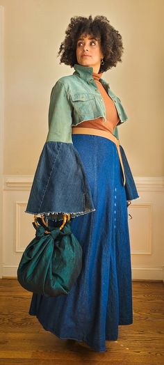 a woman dressed in an old fashion outfit and carrying a purse, standing on a hard wood floor