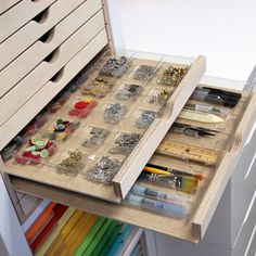 an open drawer with lots of crafting supplies in it and some drawers on the side