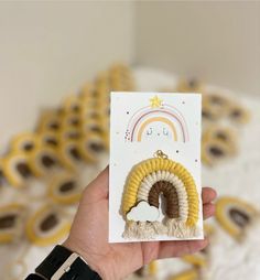 a person holding up a card with some type of brooch in the shape of a rainbow