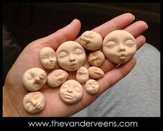 there are many small faces in the palm of someone's hand, all made out of clay