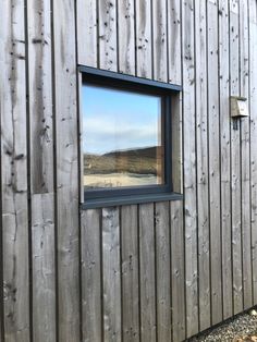 a wooden building with a small window on the side and a reflection of a mountain in it