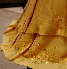 the dress is yellow and has gold embellishments on it's skirt