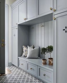 a room with white cupboards and some plants on the bench in front of it