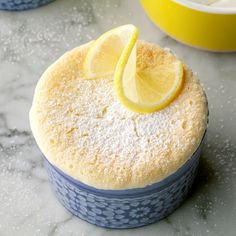 there is a small cake with lemon slices on it and two bowls in the background