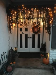 the front door is decorated for halloween with pumpkins and greenery hanging from it