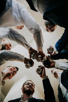 a group of men standing around each other holding cups in their hands and looking up at the sky