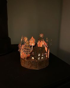 a paper crown with houses and trees on it sitting on a black table in front of a gray wall