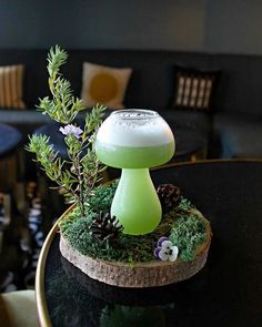 a green mushroom sitting on top of a black table next to a plant and some chairs