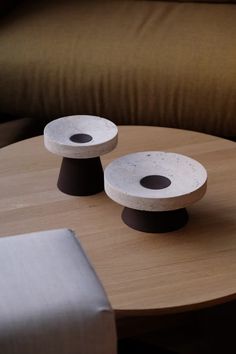 two black and white objects sitting on top of a wooden table next to a brown couch