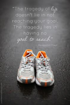 a pair of running shoes sitting on top of a road with a quote above it