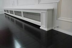 a white radiator sitting on top of a black floor next to a wall